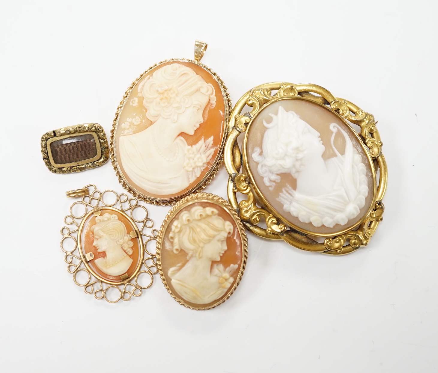 Two modern 9ct gold mounted oval cameo shell pendant brooches, largest 42cm and two other mounted oval cameo shell pendant or brooches and a mourning brooch (a,f,).
